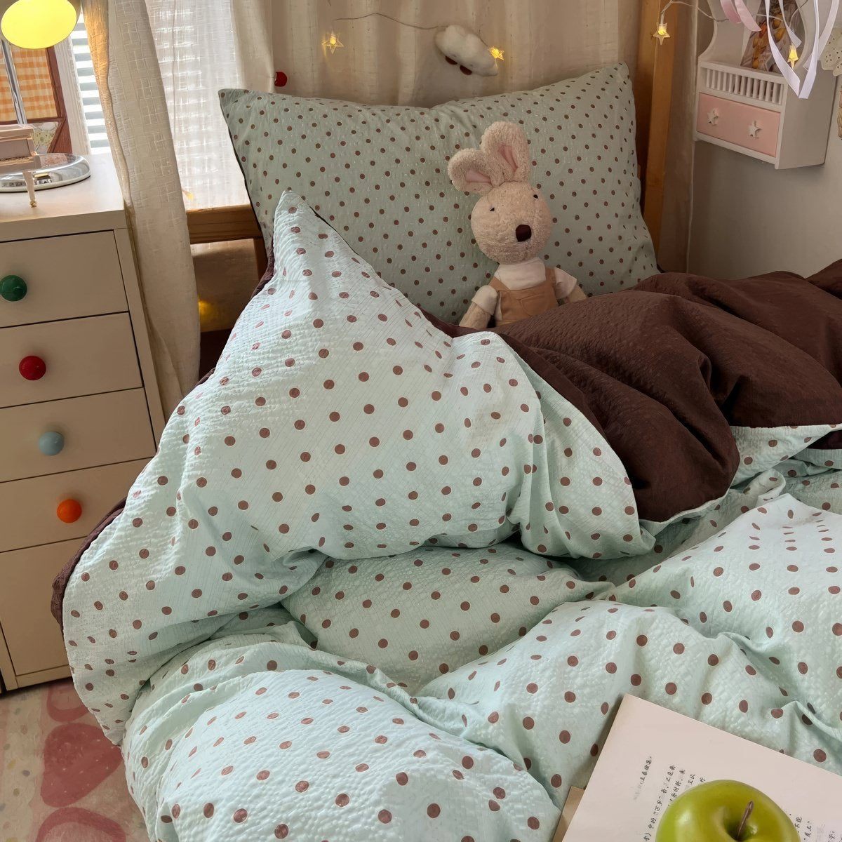 Mint green bubble crinkle bedding set with brown polka dots on a cozy bedroom bed