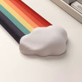 A rainbow-themed ergonomic wrist rest set, including a cloud-cushioned mouse pad and a matching keyboard wrist support, designed with a gradient rainbow pattern and soft white cloud accents