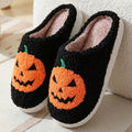 Plush Halloween slippers with embroidered jack-o’-lantern pumpkin in white and black.