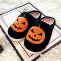 Plush Halloween slippers with embroidered jack-o’-lantern pumpkin in white and black.