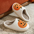 Plush Halloween slippers with embroidered jack-o’-lantern pumpkin in white and black.