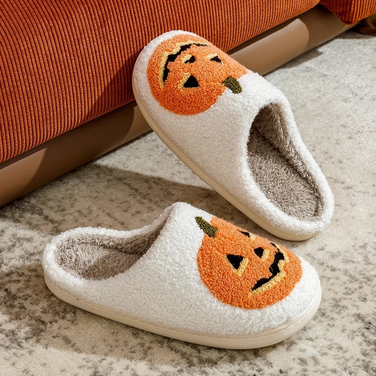 Plush Halloween slippers with embroidered jack-o’-lantern pumpkin in white and black.