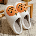 Plush Halloween slippers with embroidered jack-o’-lantern pumpkin in white and black.