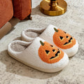 Plush Halloween slippers with embroidered jack-o’-lantern pumpkin in white and black.