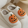 Plush Halloween slippers with embroidered jack-o’-lantern pumpkin in white and black.