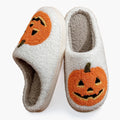 Plush Halloween slippers with embroidered jack-o’-lantern pumpkin in white and black.